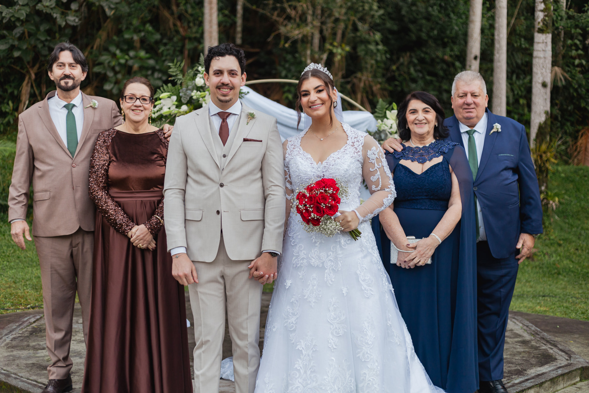 Noivos com suas famílias posando juntos após a cerimônia de casamento no campo