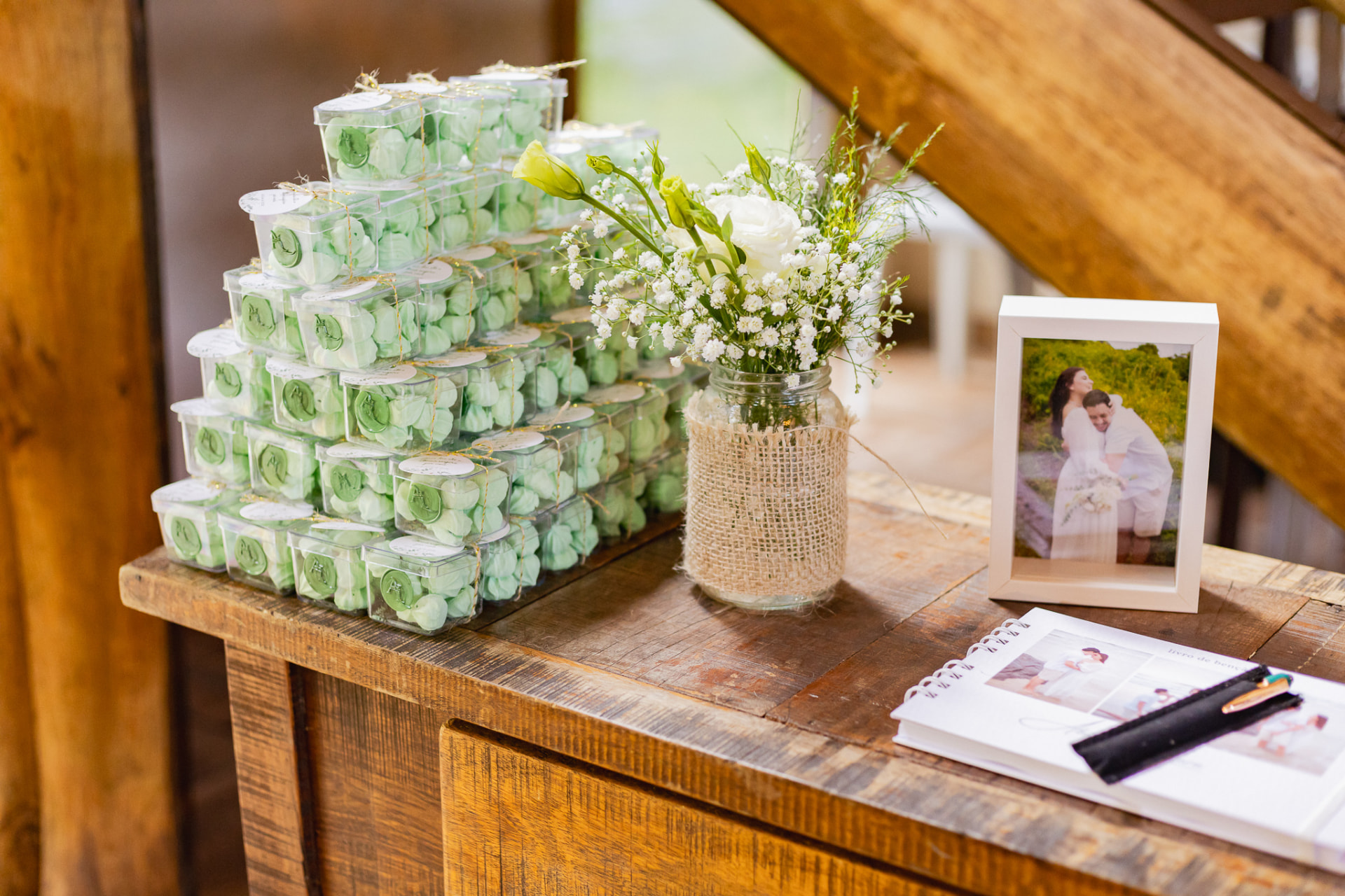 Lembrancinhas de casamento artesanais empilhadas na mesa de boas-vindas ao lado de flores brancas